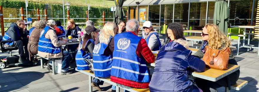 Deelnemers aan de busrit praten na op een terras